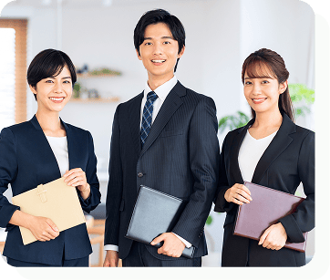 スーツを着た女性2名と男性1名が正面を見て微笑んでいる